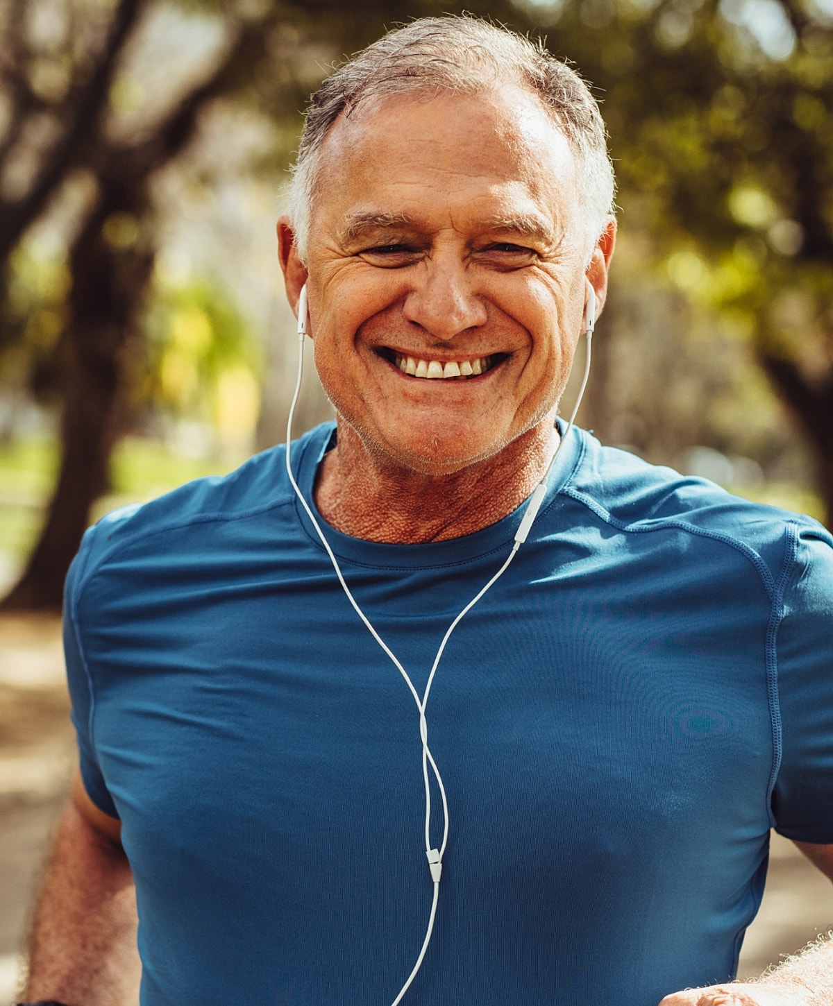 Smiling man exercising with earbuds outdoors.
