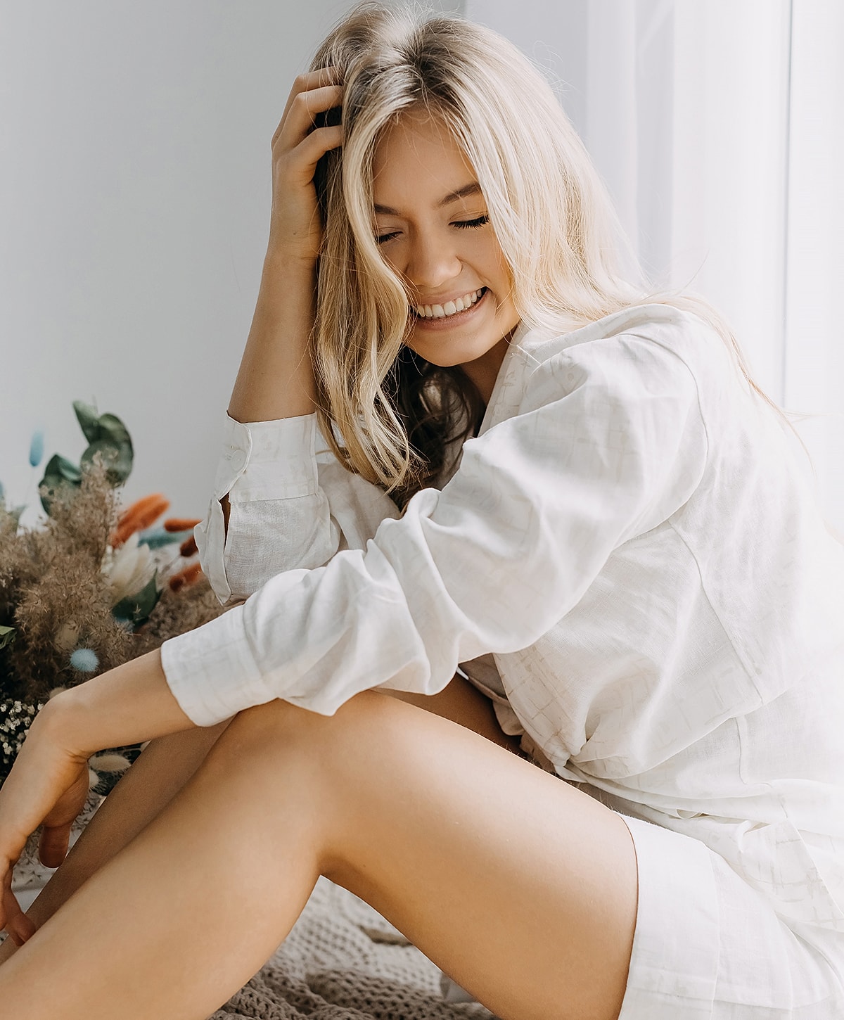 Smiling woman with blonde hair in cozy setting.