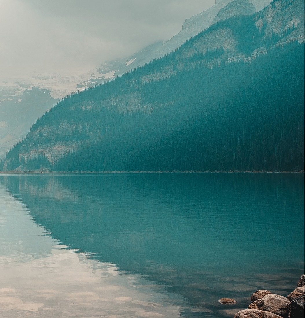 Misty lake reflecting mountains and trees.