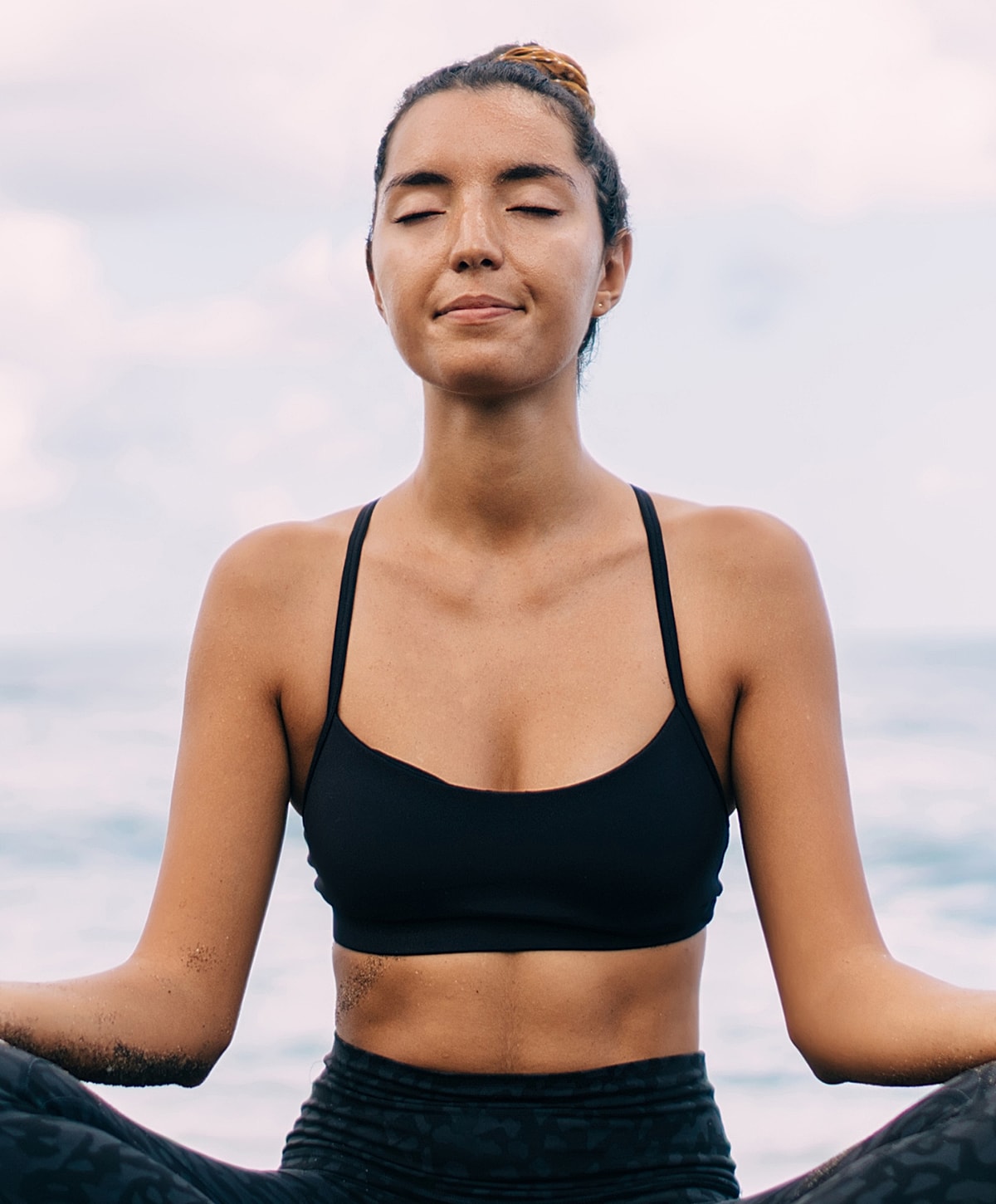 Woman meditating by the ocean shore.