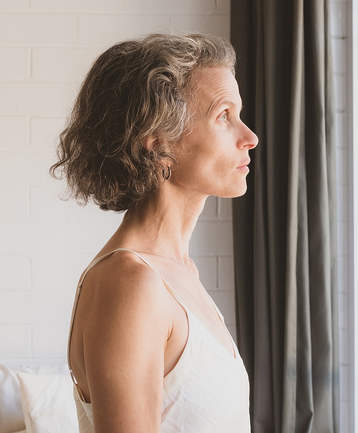 Woman gazing thoughtfully out of a window.
