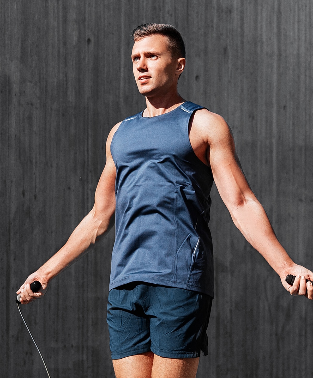 Man exercising with a jump rope indoors.