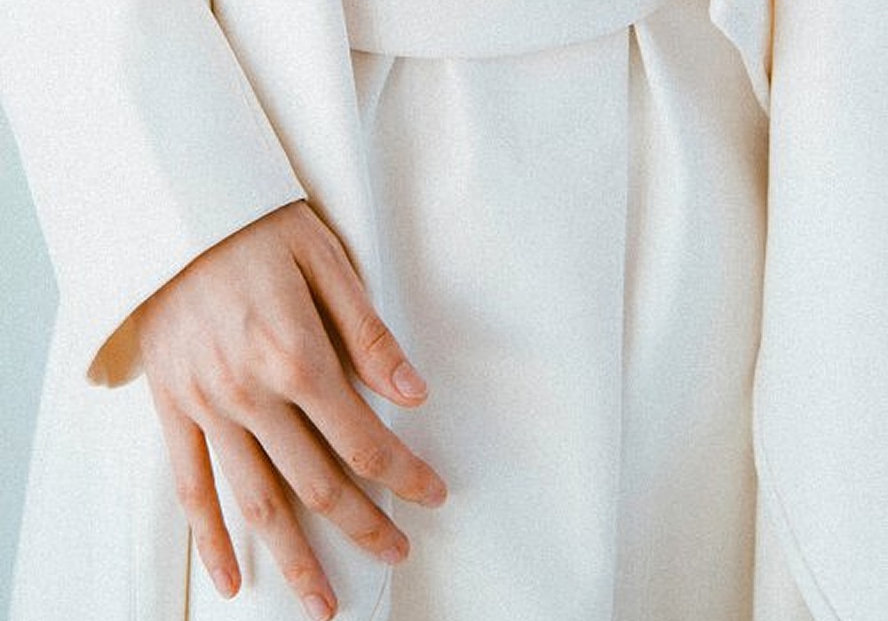 Close-up of a hand on white fabric.