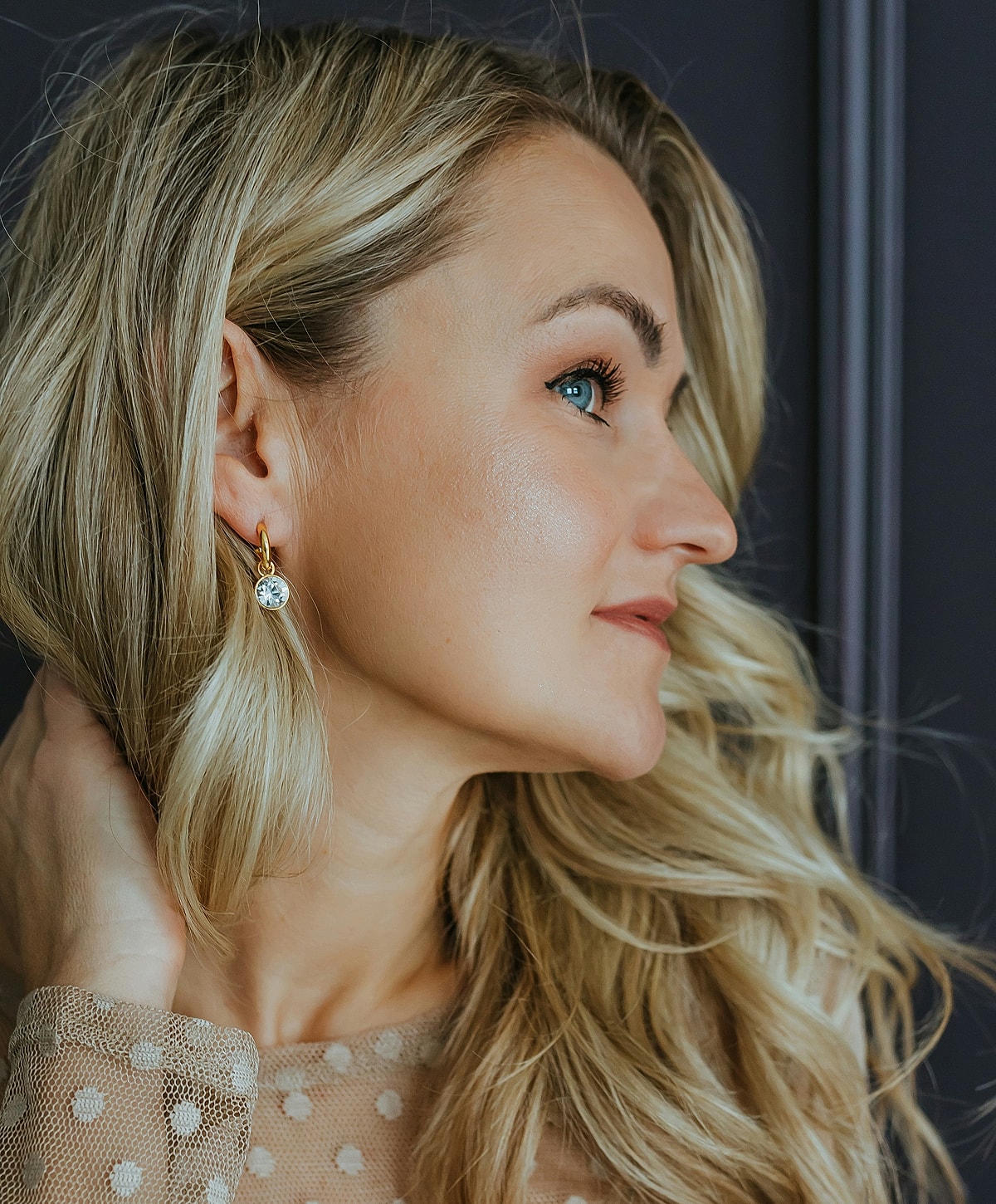 Woman with earrings and wavy blonde hair.