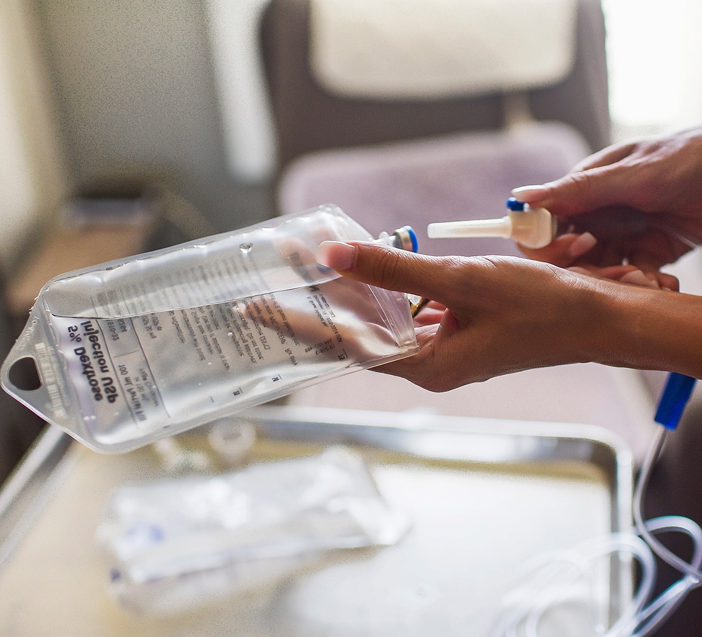 Person handling IV fluid bag in healthcare setting.