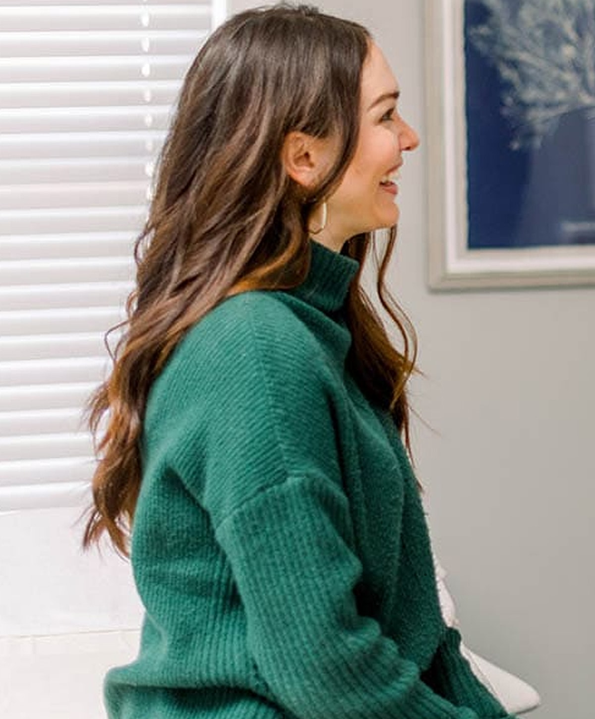 Woman smiling in a green sweater profile view.