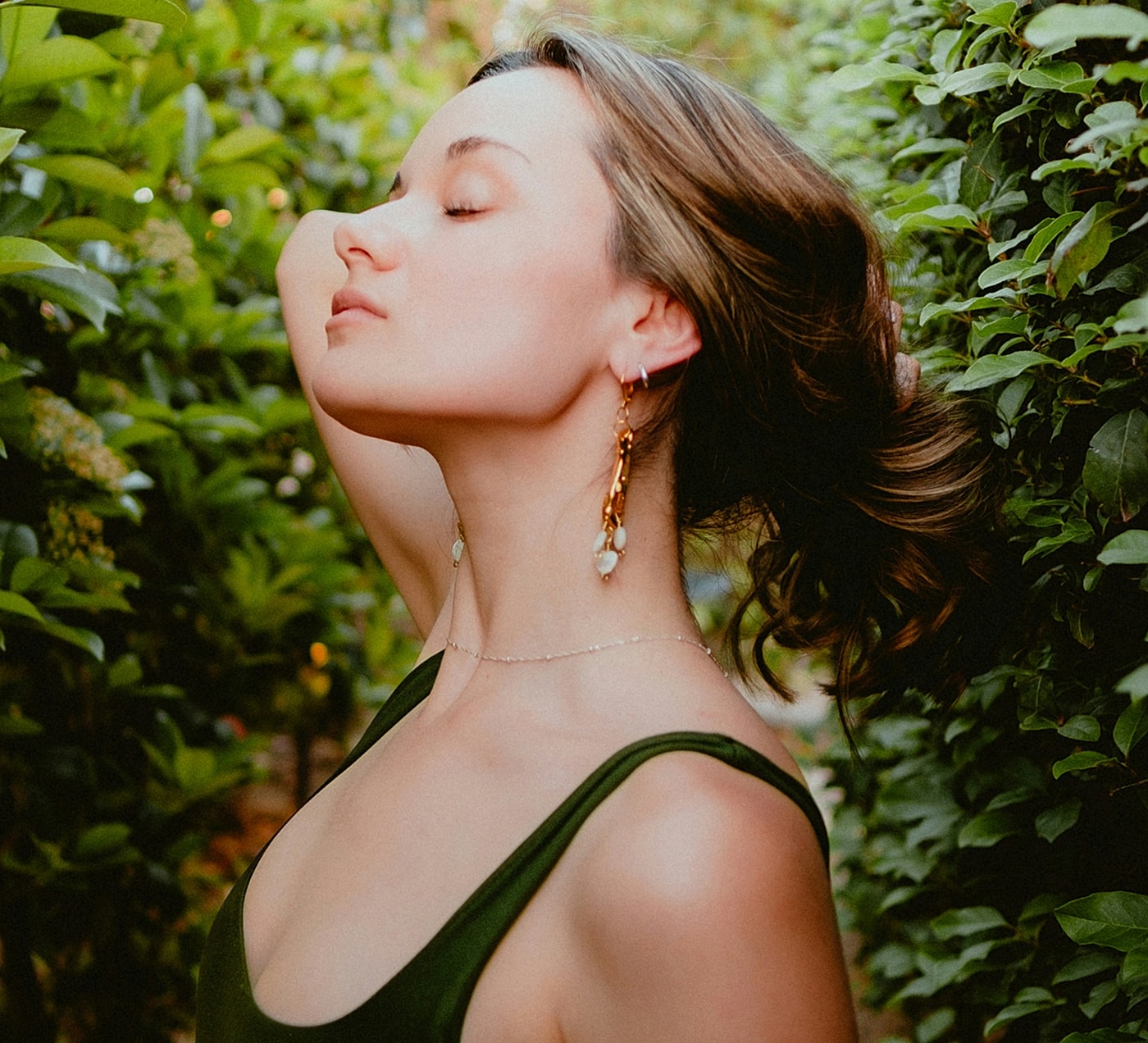 Woman in green dress amidst lush greenery.
