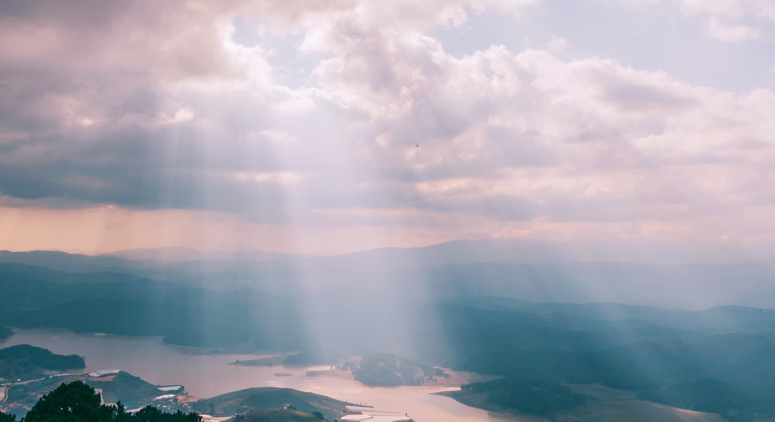 Sunlight streaming through clouds over landscape.