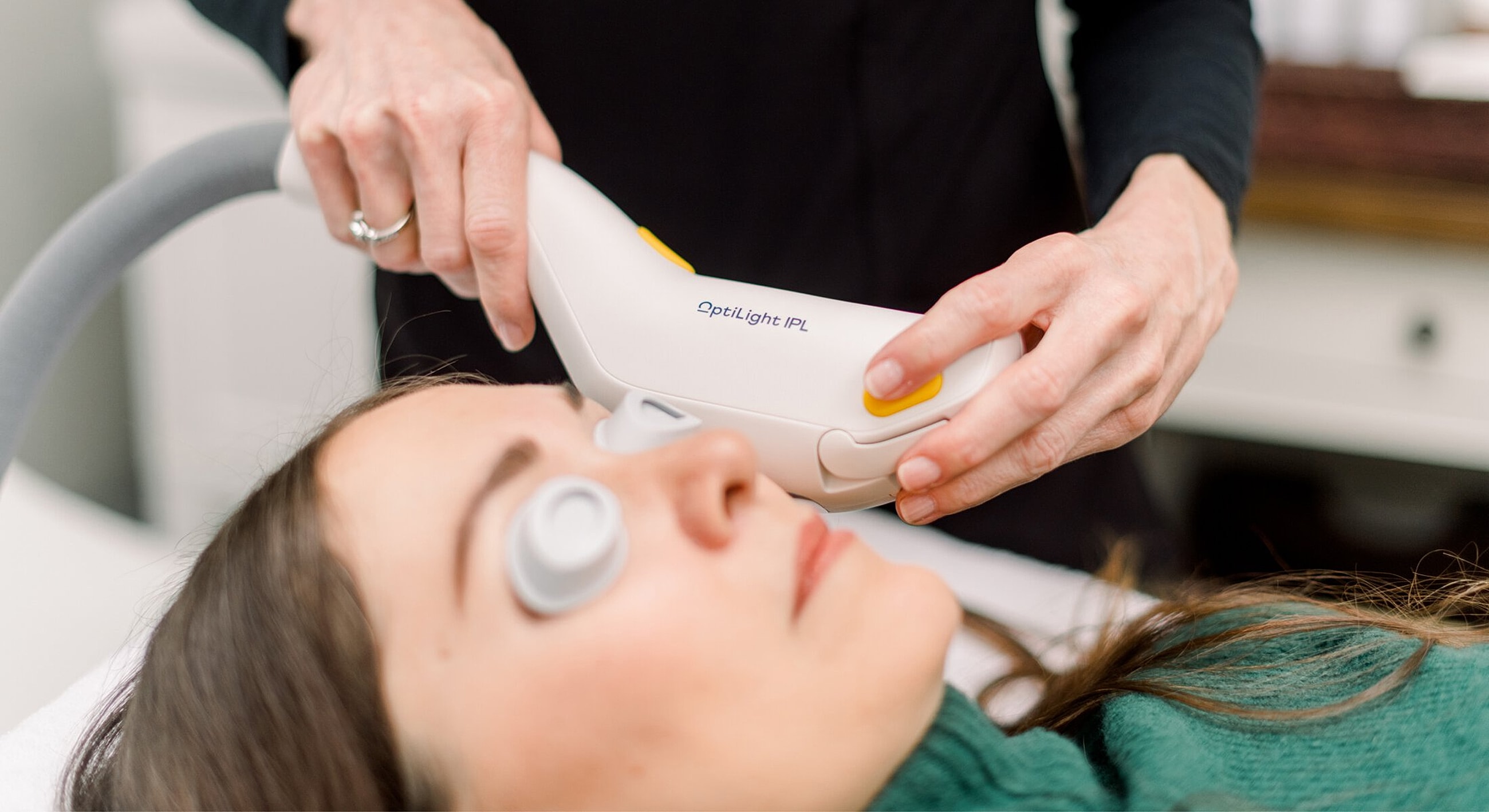 Woman receiving facial treatment with IPL device.