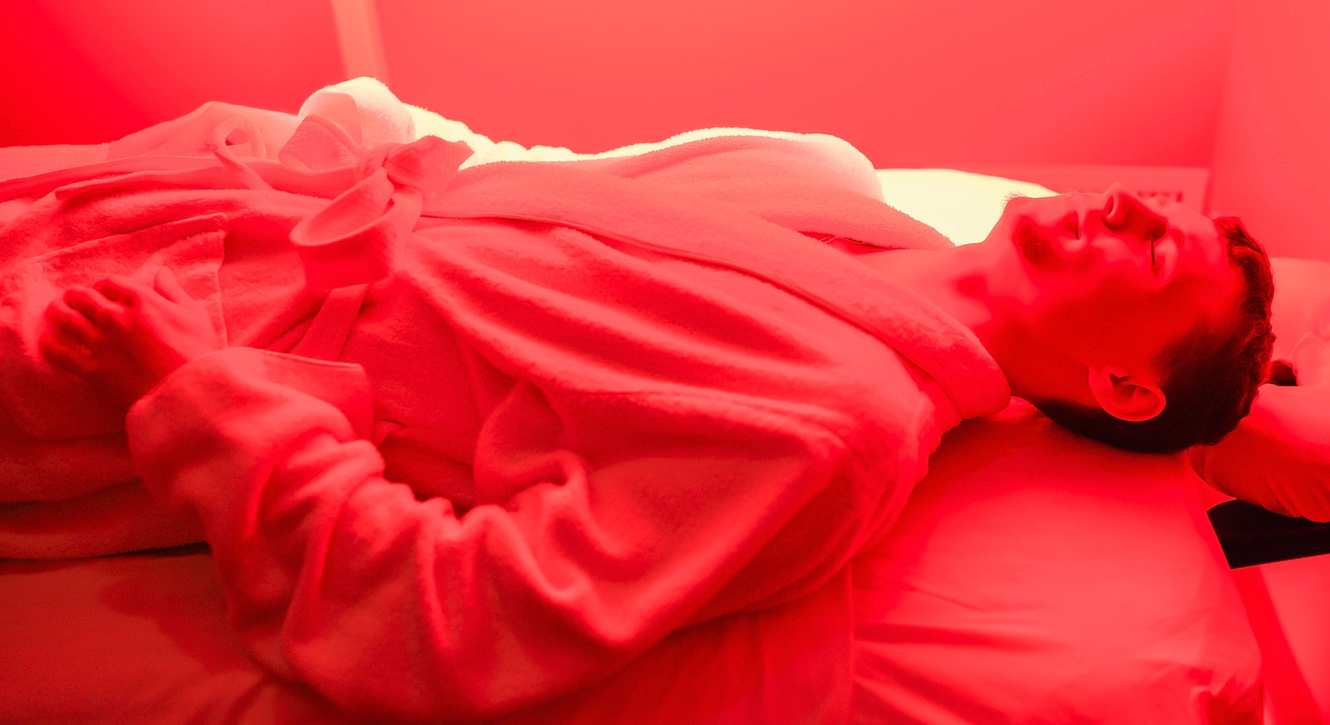 Person relaxing in red light therapy room.