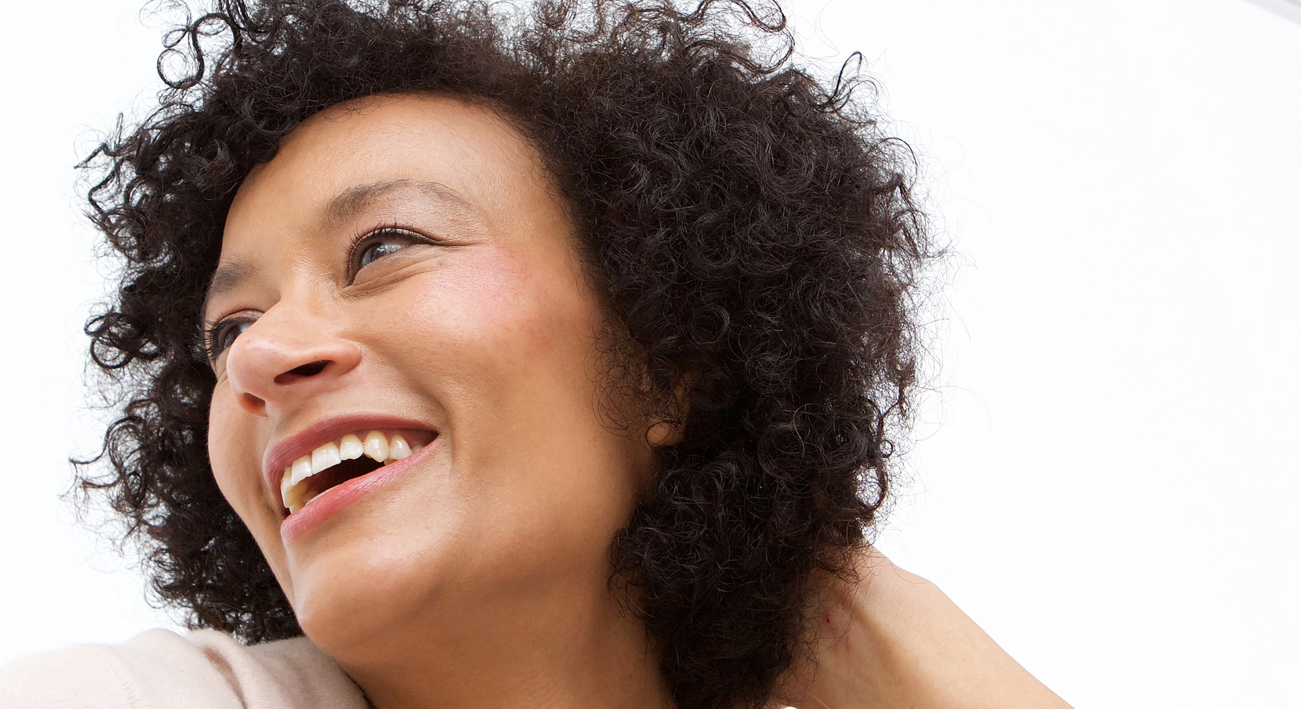 Smiling woman with curly hair against white background