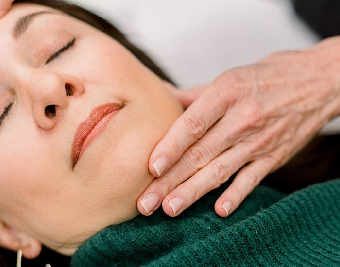 Facial massage relaxing woman in green sweater.
