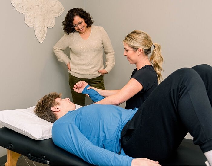 Physical therapy session with two women assisting.