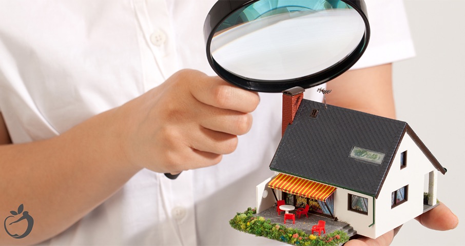 man with magnifying glass looking closely at a model house