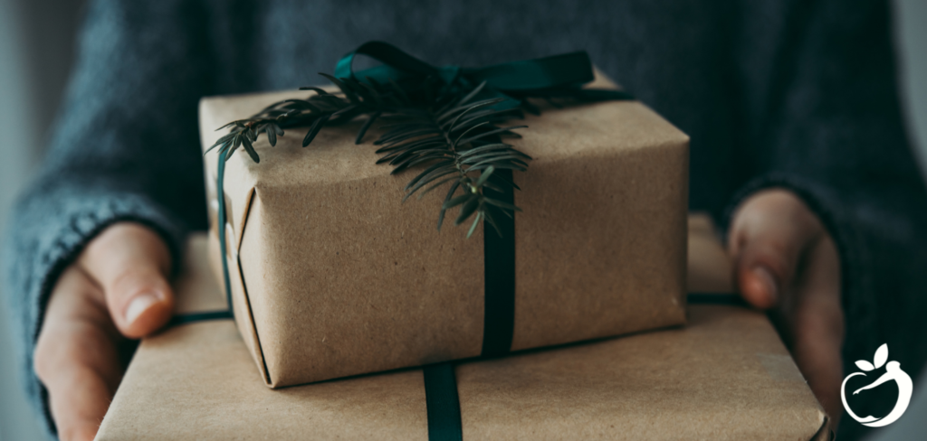 Blog Post Header Image - 5 HealthyGift Ideas. Image of person holding two brown paper wrapped gifts.