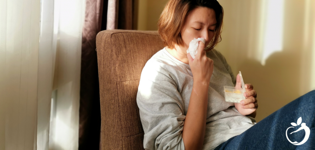 woman sitting in a chair wiping her nose with tissue