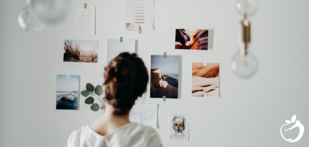 woman standing and looking at her vision board on the wall