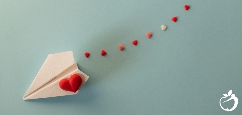 paper plane with a heart on it against a baby blue background