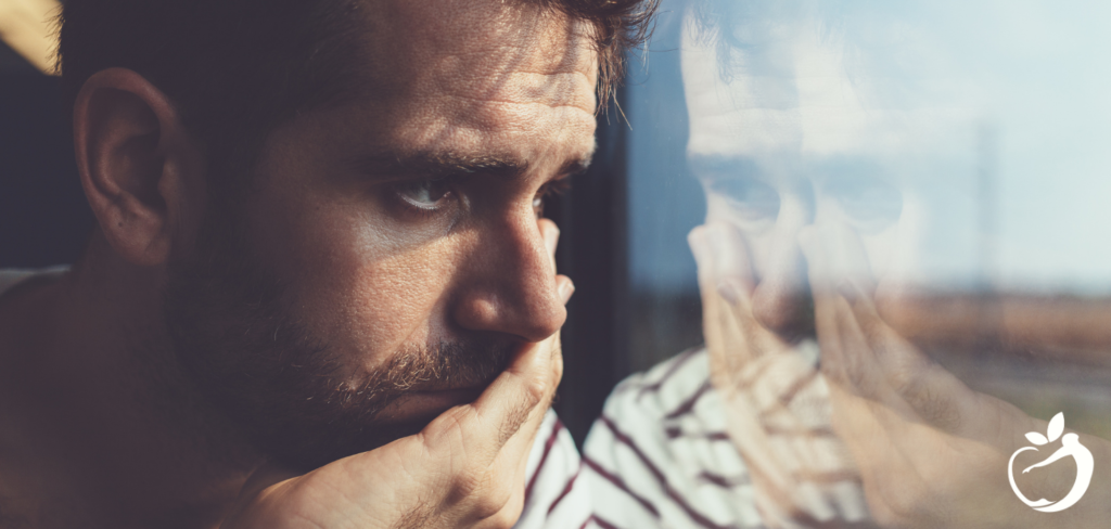 man looking out the window with his chin in his hand