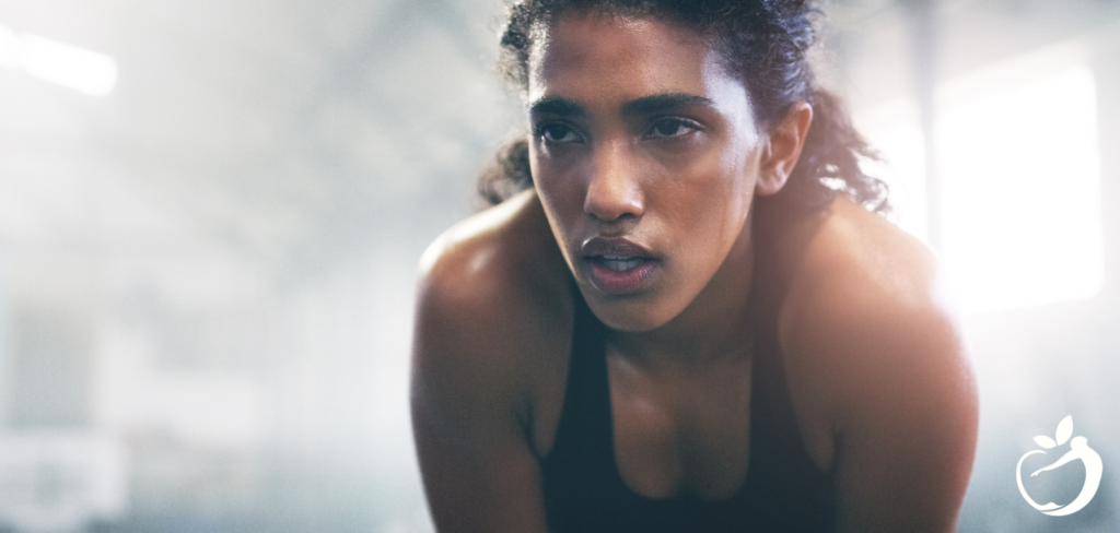 woman in a sports bra leaning over with her hands on her knees