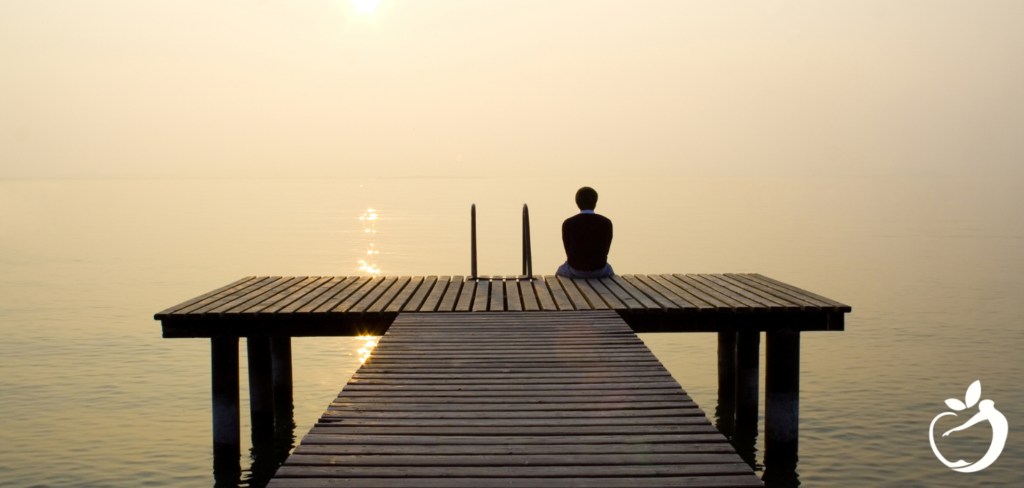 person sitting at the end of a long pier