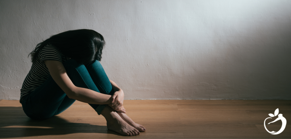 woman sitting on the floor with her head between her knees