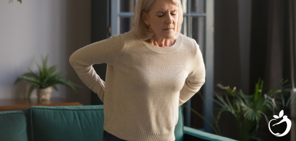 woman with her hands on her lower back wincing in pain