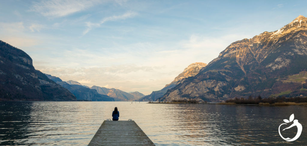 person sitting at the end of a dock meditating