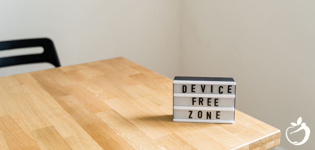 Image of a table with a sign on it that says "device free zone" demonstrating digital detox efforts.