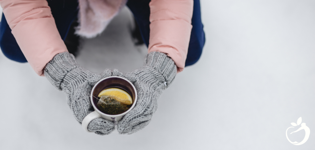 a person with mittens on holding a cup of tea