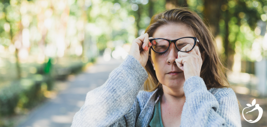 woman lifting up her glasses to rub her eyes