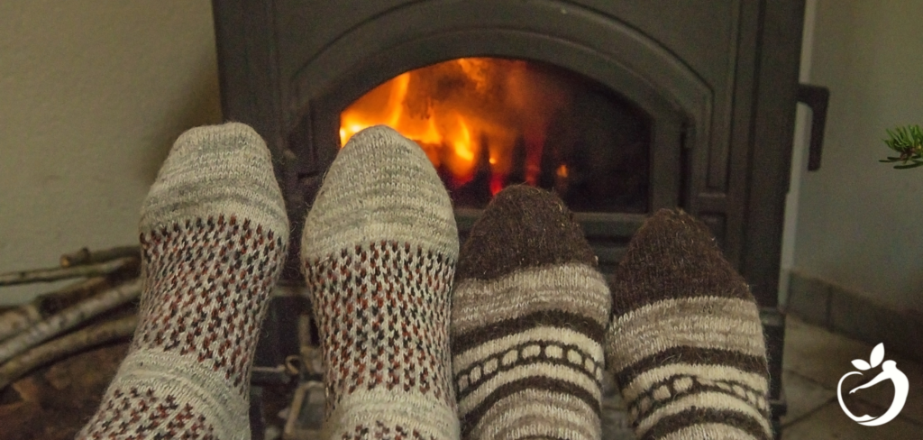 two people's feet in thick socks next to a fireplace