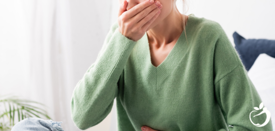 Image of a woman holding her hand over her mouth, suffering from nausea. Read our top tips for nausea.