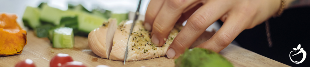 person cutting up chicken breast and veggies