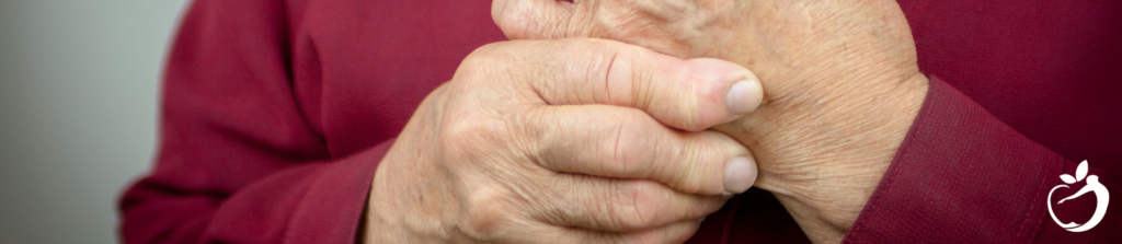 a person with autoimmune disease rubbing their swollen knuckles