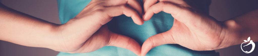 person making a heart-shape with their hands over their stomach