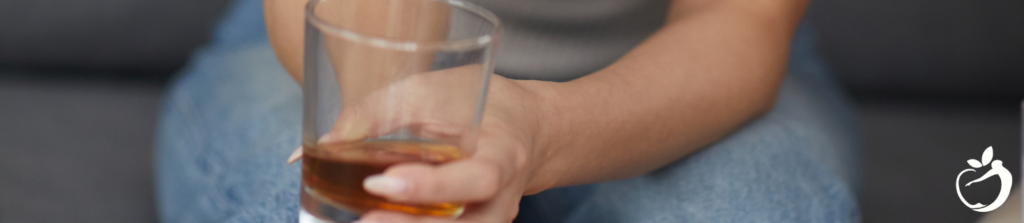 someone sitting on a couch drinking alcohol out of a small bar glass