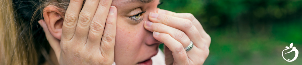 Showing an image of a woman holding her nose, and head, experiencing flu-like symptoms associated with Lyme disease.