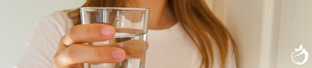 How to Avoid Jet Lag: Dr. Ellen’s Pro Tips. Image of person holding a glass of water, as it relates to hydrating.