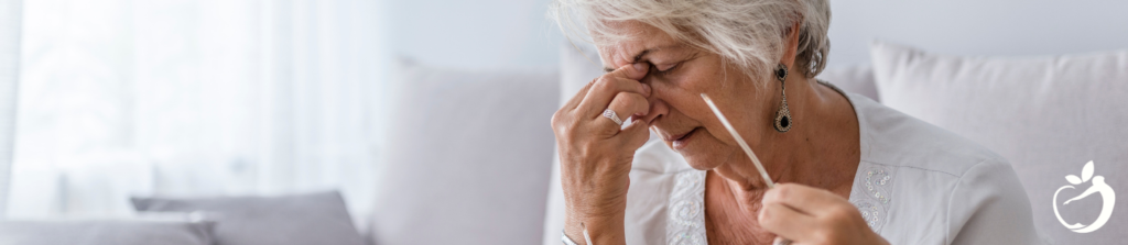 older women pinching the bridge of her nose while wincing