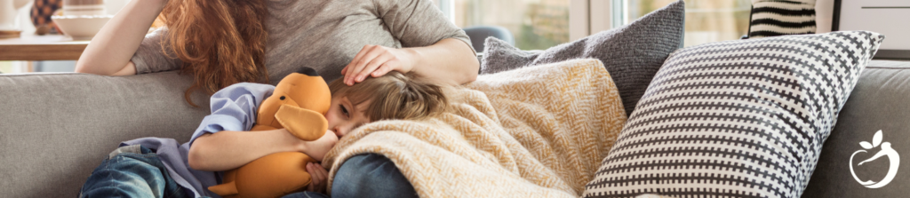 child laying on their mother's lap on the couch