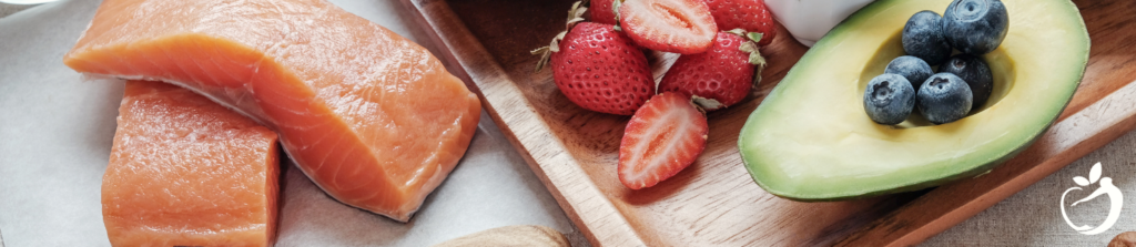 table with salmon, strawberries, avocado, and blueberries on it