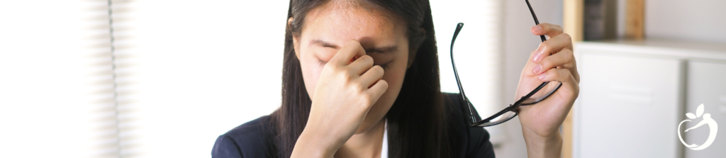 woman in a suit pinching the bridge of her nose