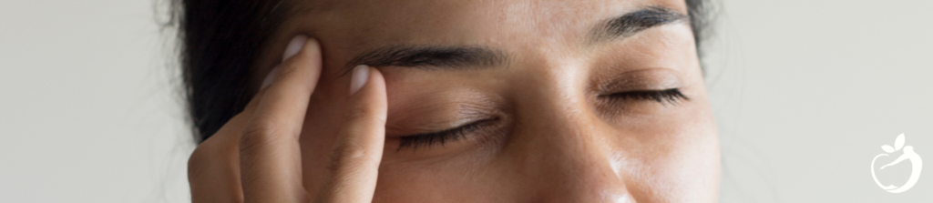 woman wincing while touching her head