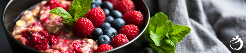 oatmeal and berries in a black bowl with mint garnish