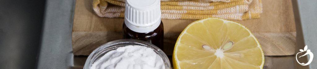 closeup of essential oils, a sliced lemon, and baking soda