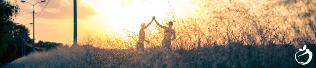 Image of two people holding hands at sunset conquering resistance by using our tips for success.