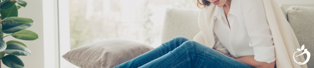 woman sitting on a bed clutching her abdomen