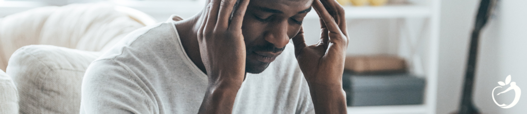 man sitting down with his hands on his temples