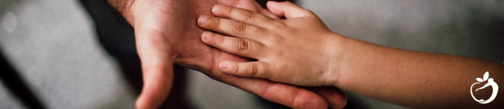 What To Do When PANS/PANDAS Is Expected. Image of a child's hand on top of an adults hand. A tender moment.